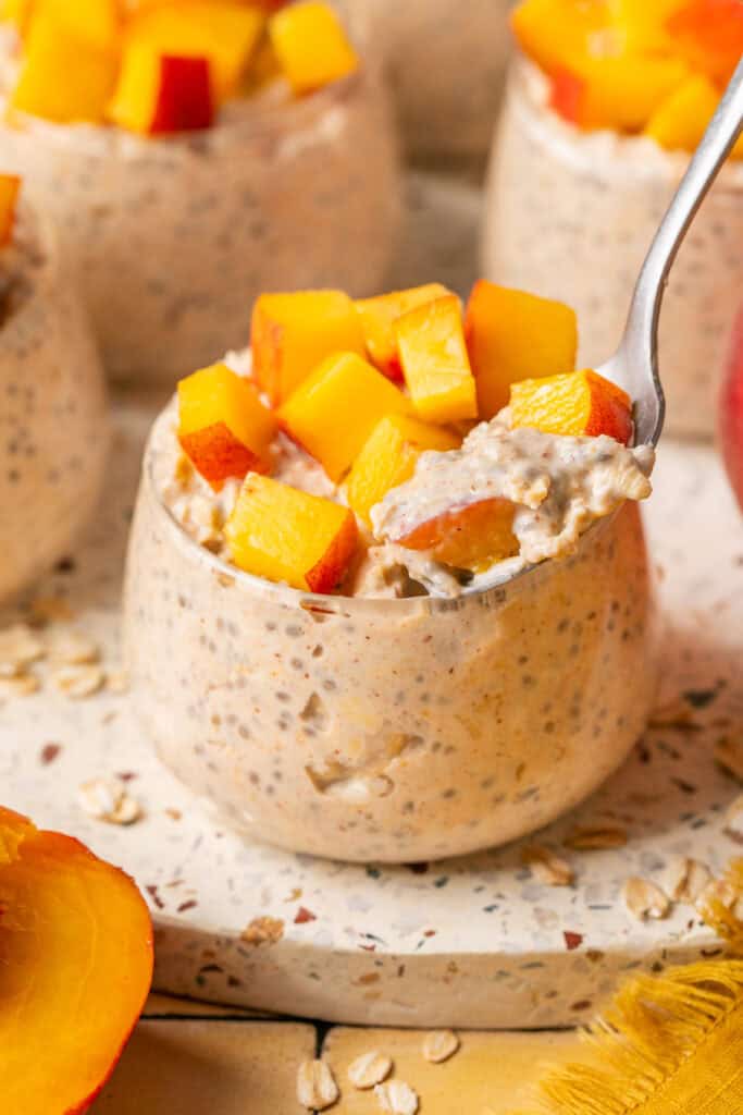 overnight oats topped with peaches and spoon