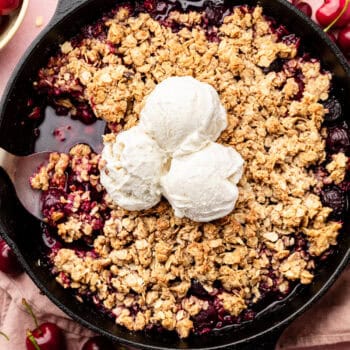 cherry crisp in skillet topped with ice cream