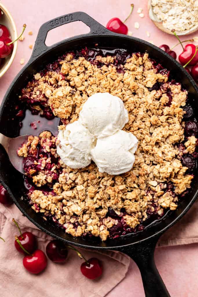 cherry crisp in skillet topped with ice cream