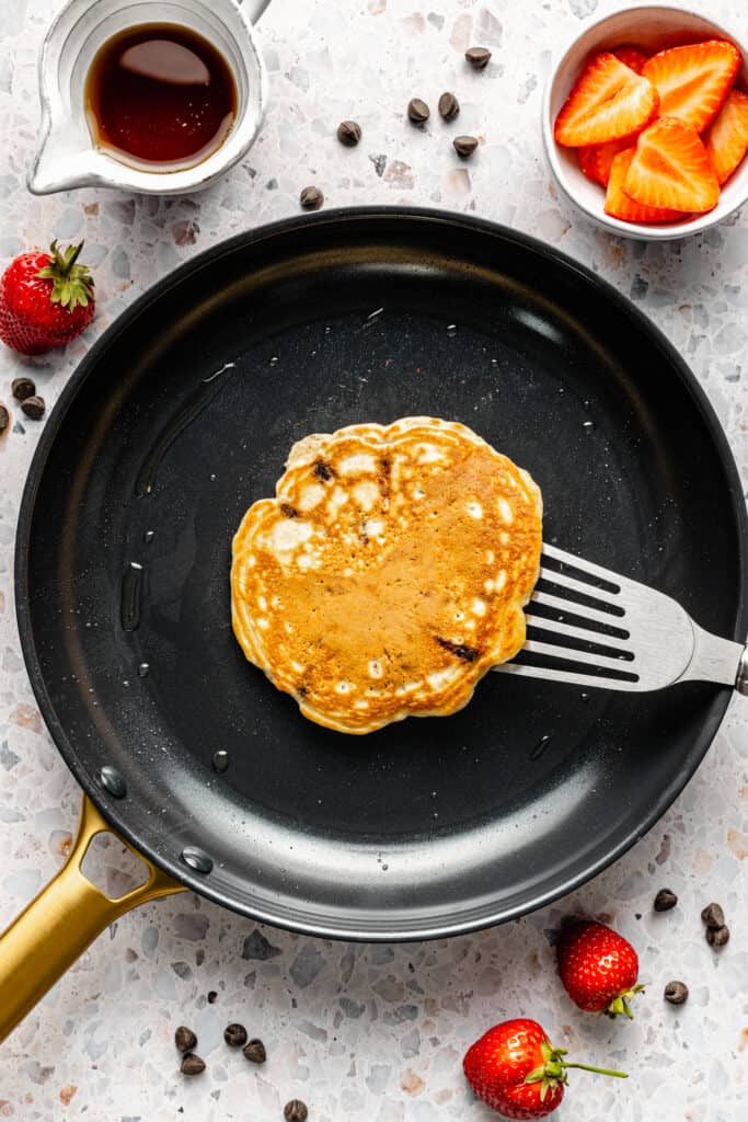 pancake cooking in skillet with spatula