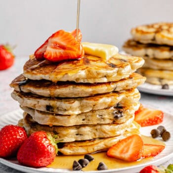 stack of chocolate chip pancakes with strawberries and maple syrup