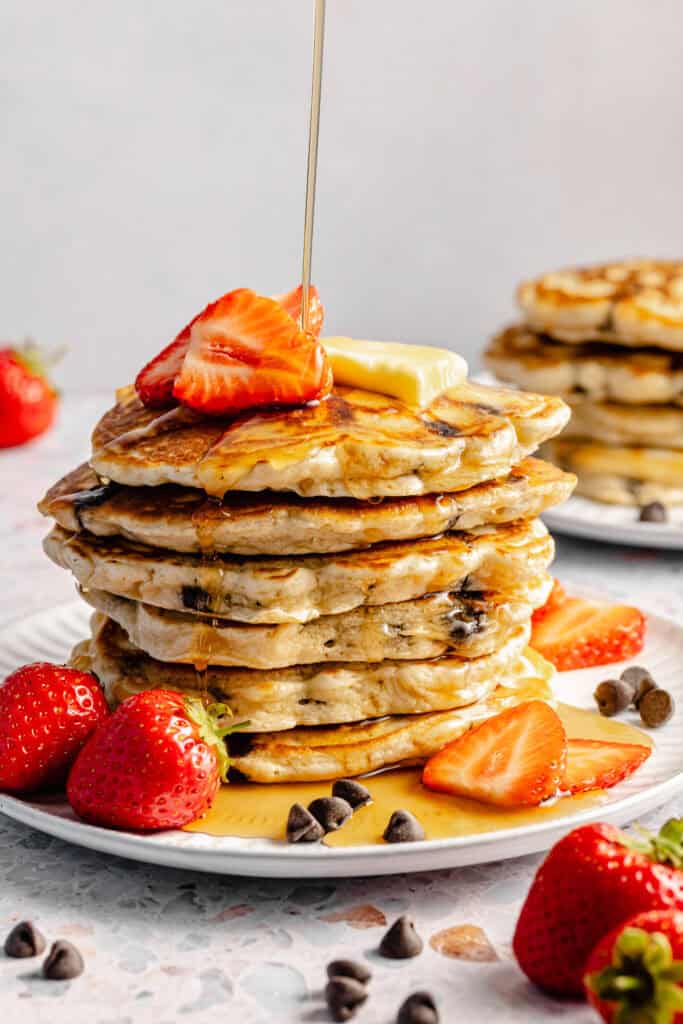 stack of chocolate chip pancakes with strawberries and maple syrup