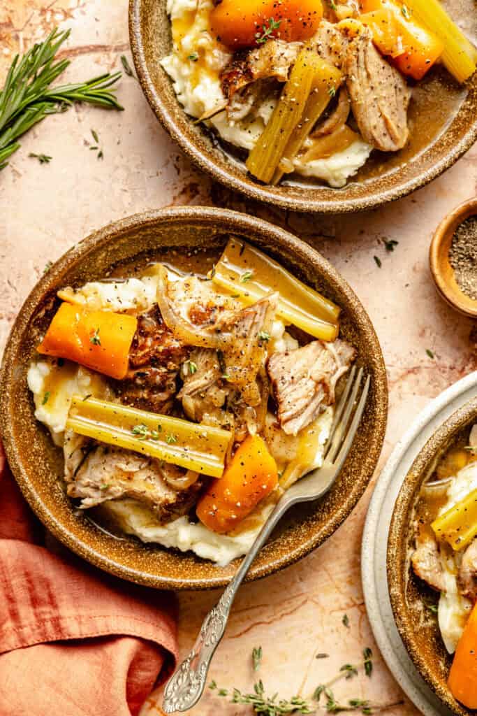 pork roast over mashed potatoes with veggies in bowl with fork