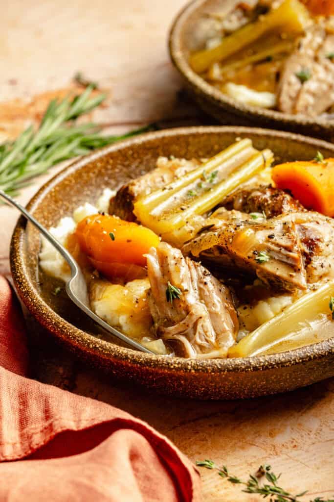 pork roast over mashed potatoes with veggies in bowl