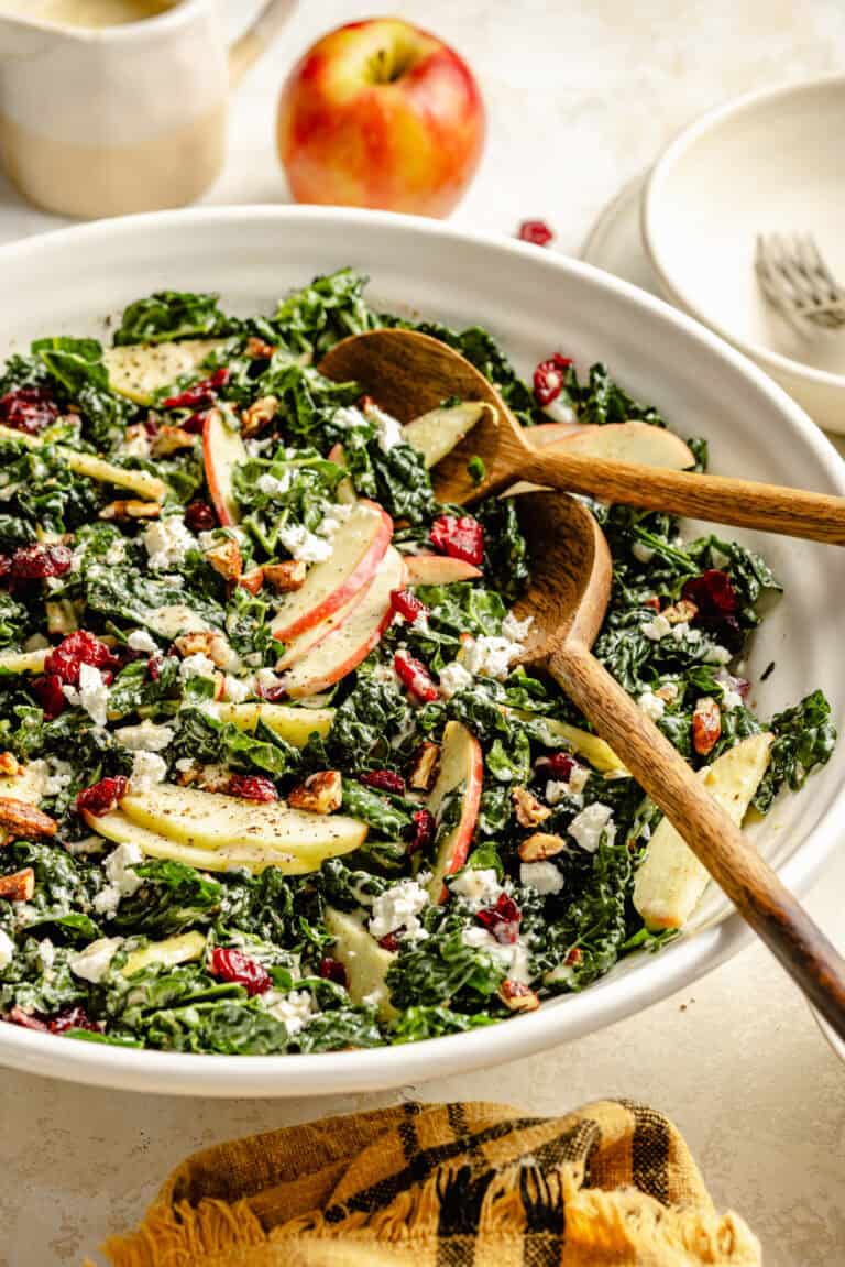 honey mustard kale salad in bowl with two wooden serving spoons