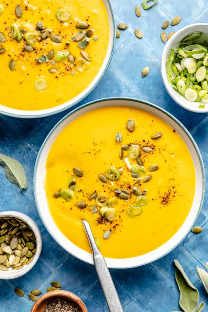 two bowls of butternut squash soup with spoons