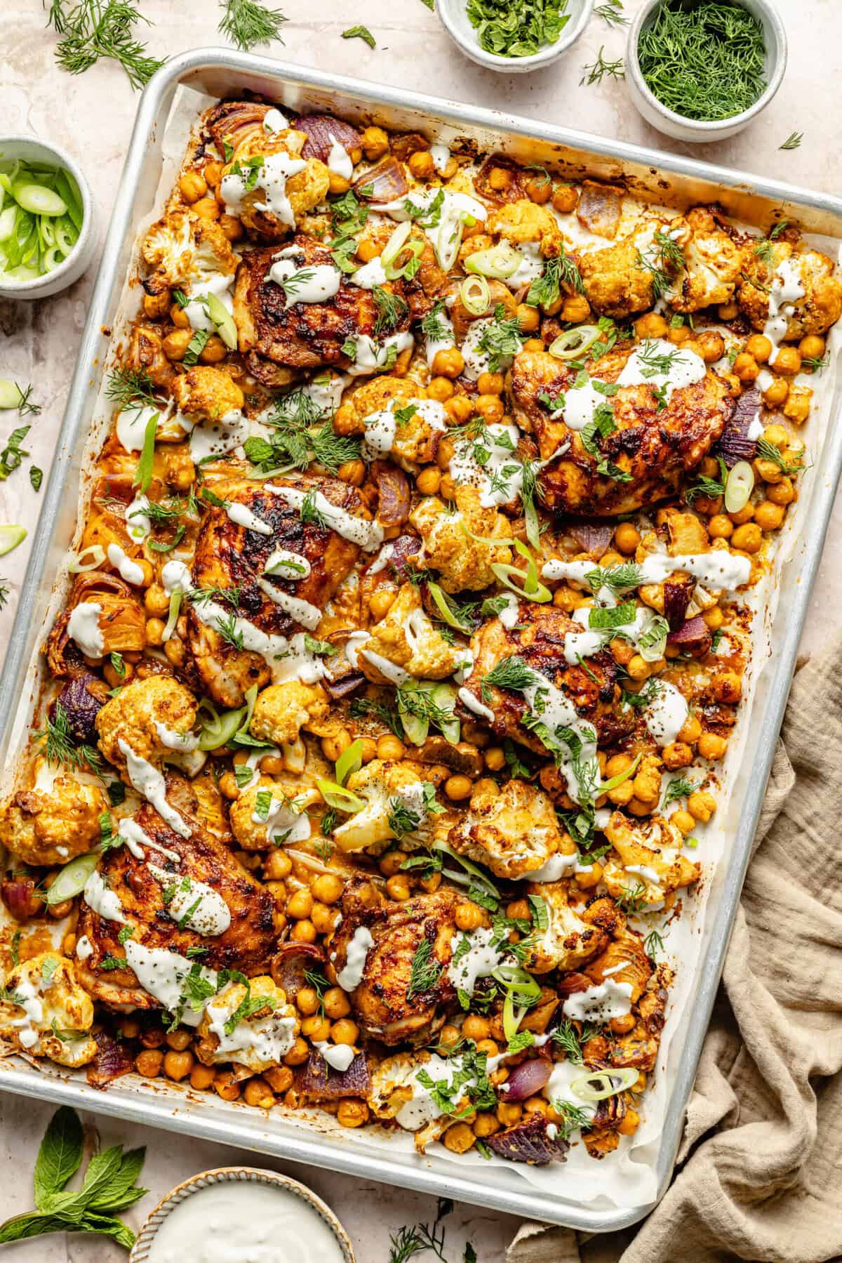 chicken and veggies on sheet pan drizzled with tahini sauce