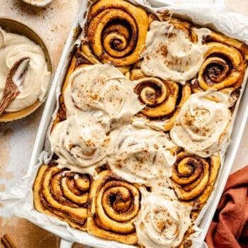 sweet potato cinnamon rolls in baking dish with cream cheese frosting