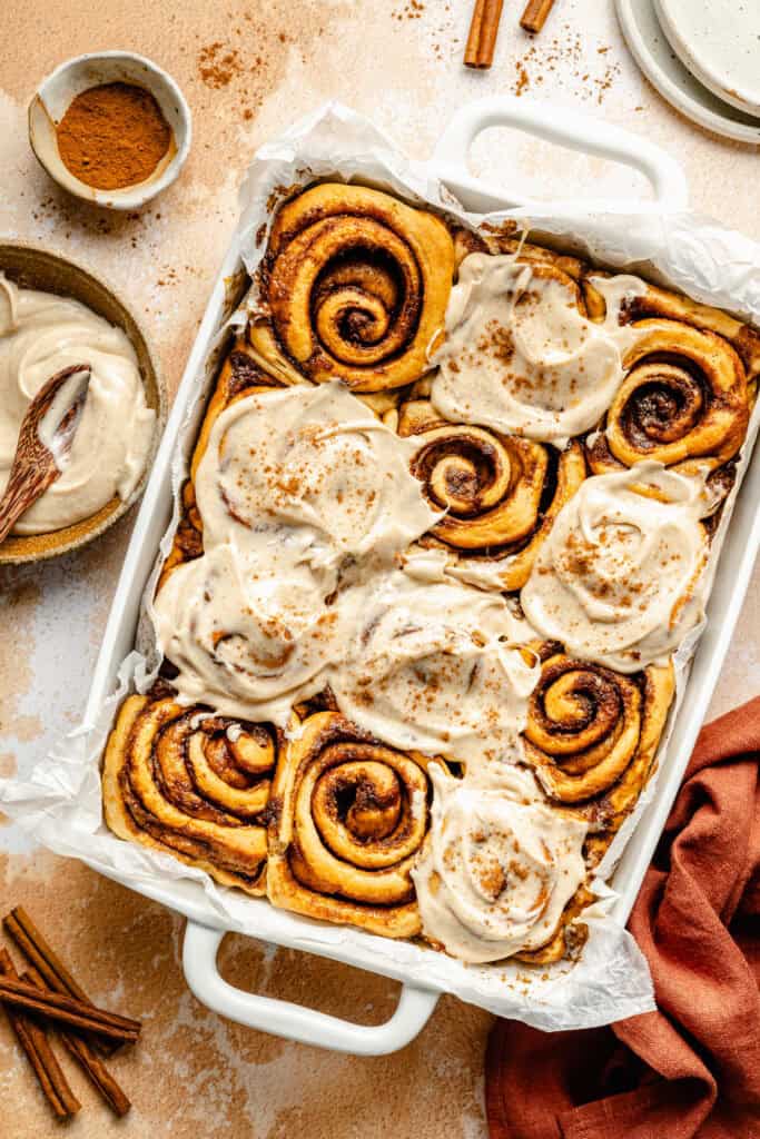 sweet potato cinnamon rolls in baking dish with cream cheese frosting