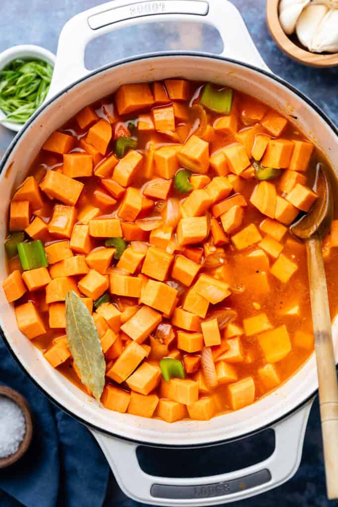 sweet potato soup ingredients in pot with wooden spoon