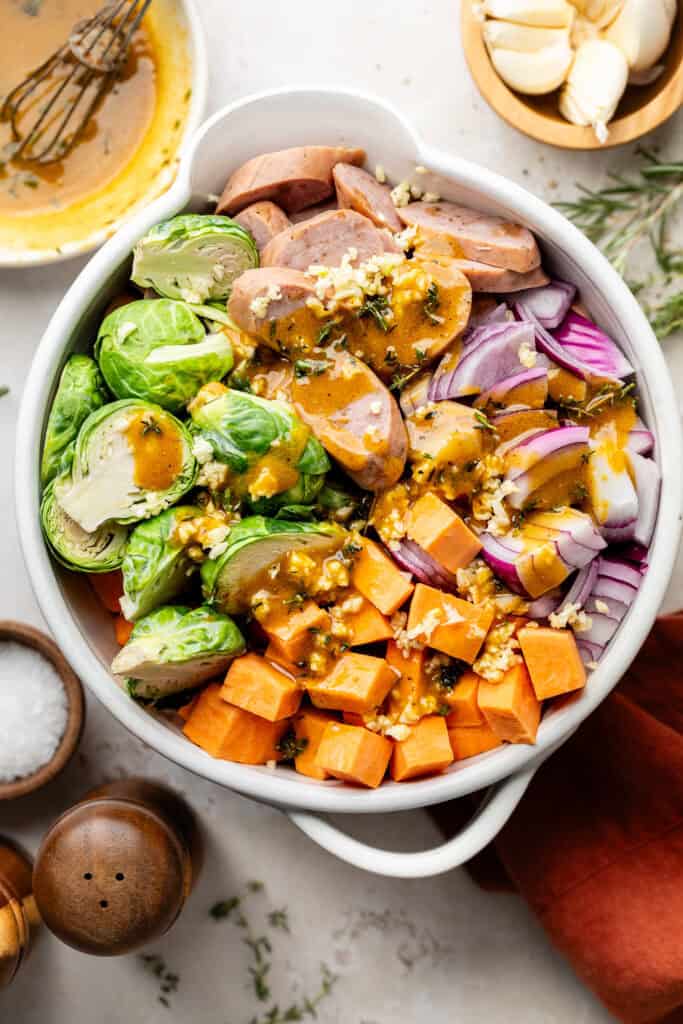 veggies and chicken sausage in mixing bowl with marinade