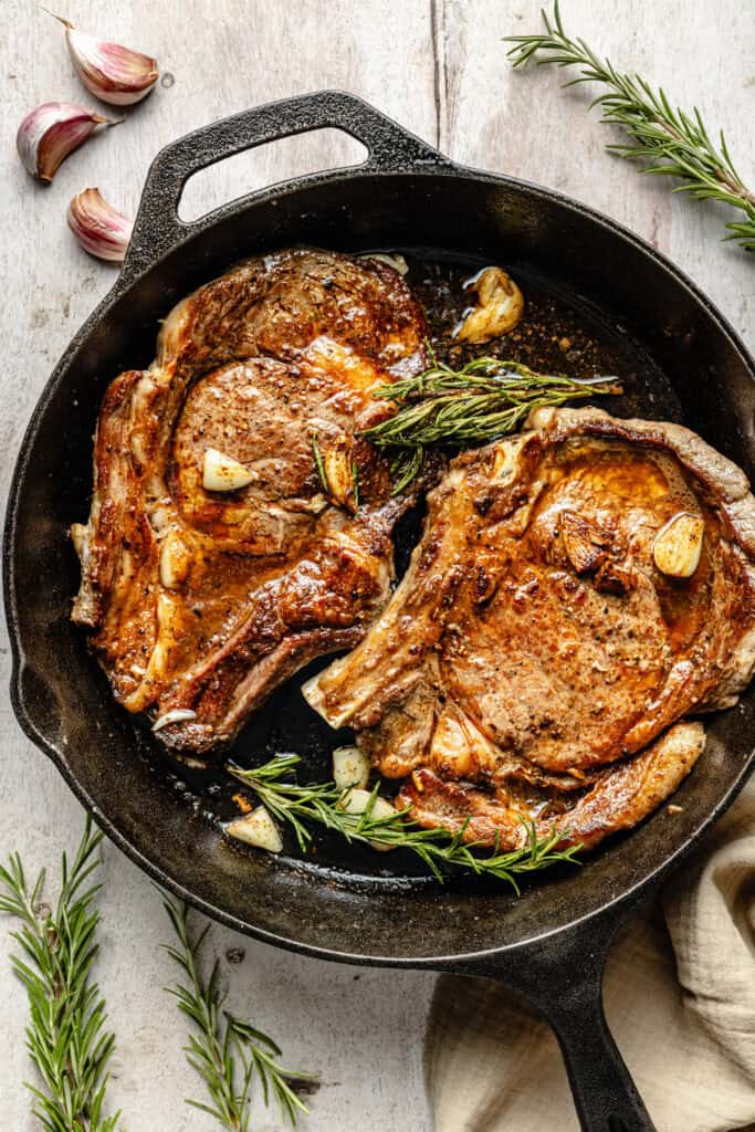 steaks in cast iron skillet with herbs and garlic