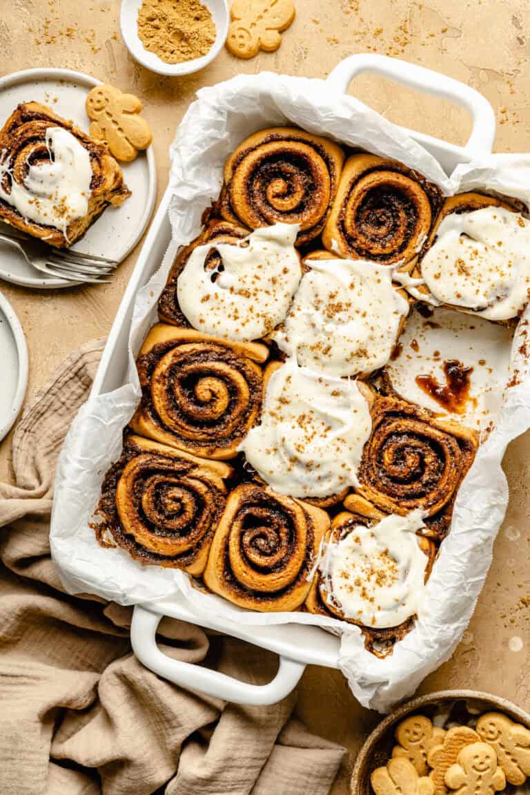 gingerbread cinnamon rolls in pan with cream cheese