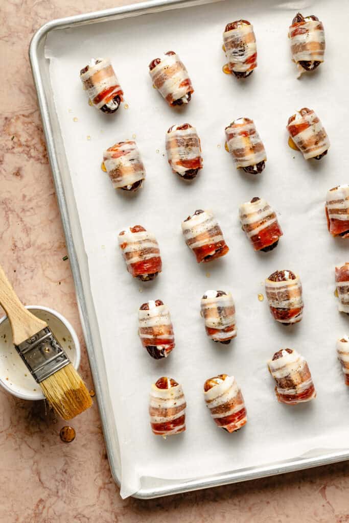 stuffed dates on baking sheet lined with parchment paper and brushed with honey