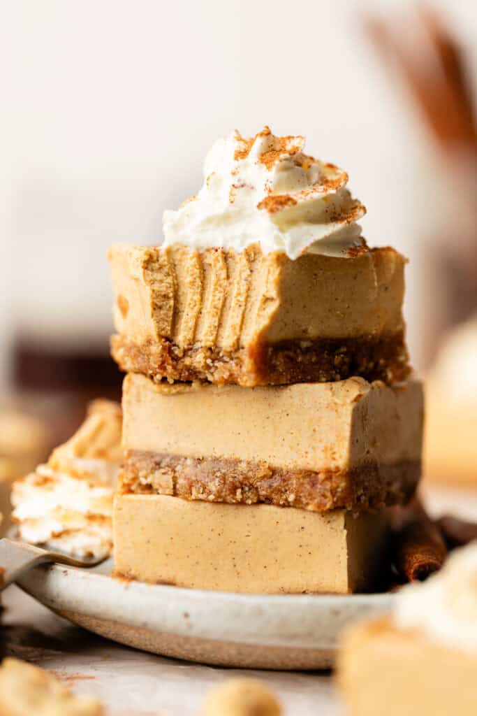 sweet potato cheesecake bars stacked on each other with whipped cream eaten with a fork