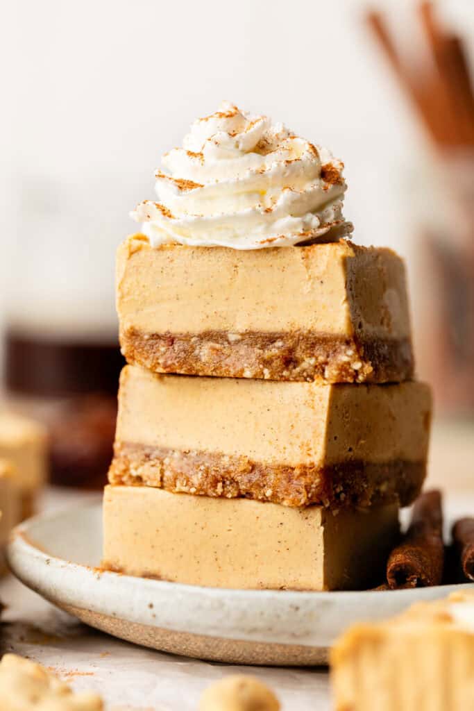sweet potato cheesecake bars stacked on each other with whipped cream