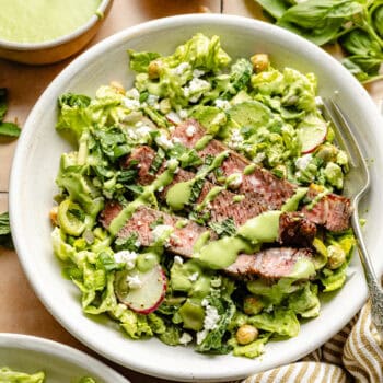 steak salad in bowl with fork and salad dressing