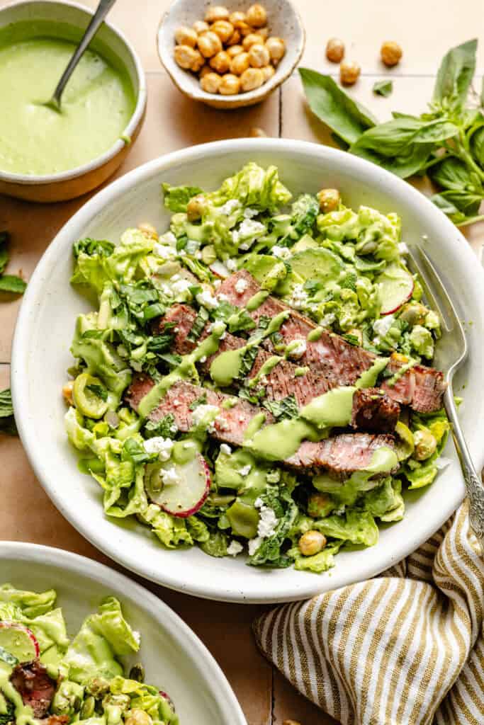 steak salad in bowl with fork and salad dressing