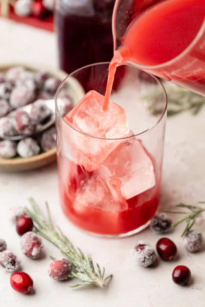 cranberry juice being poured over ice