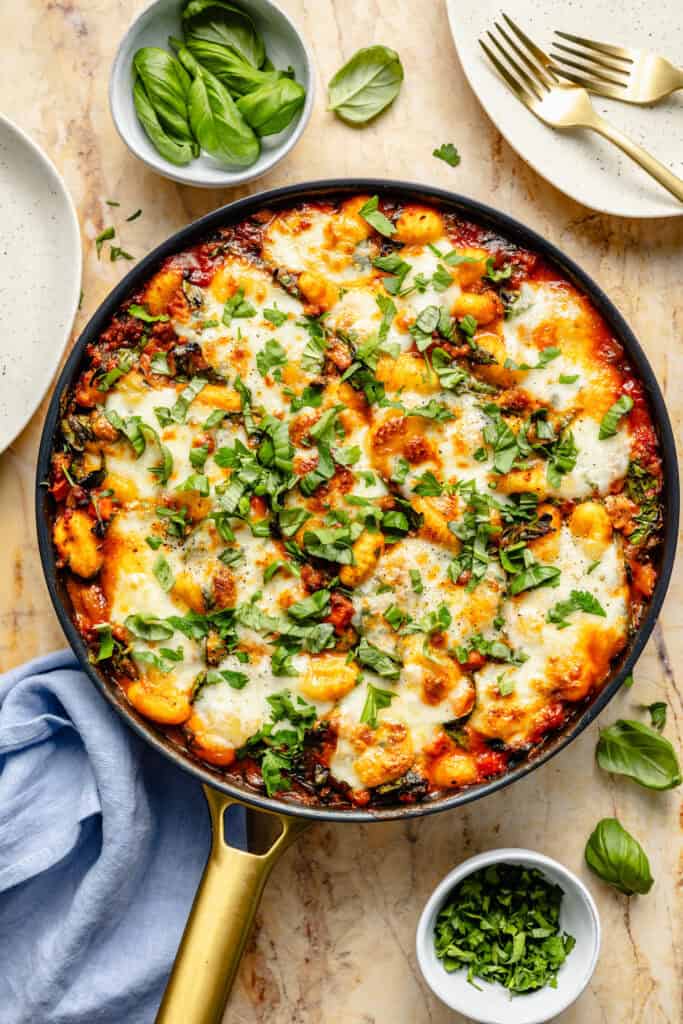 baked gnocchi in skillet topped with basil