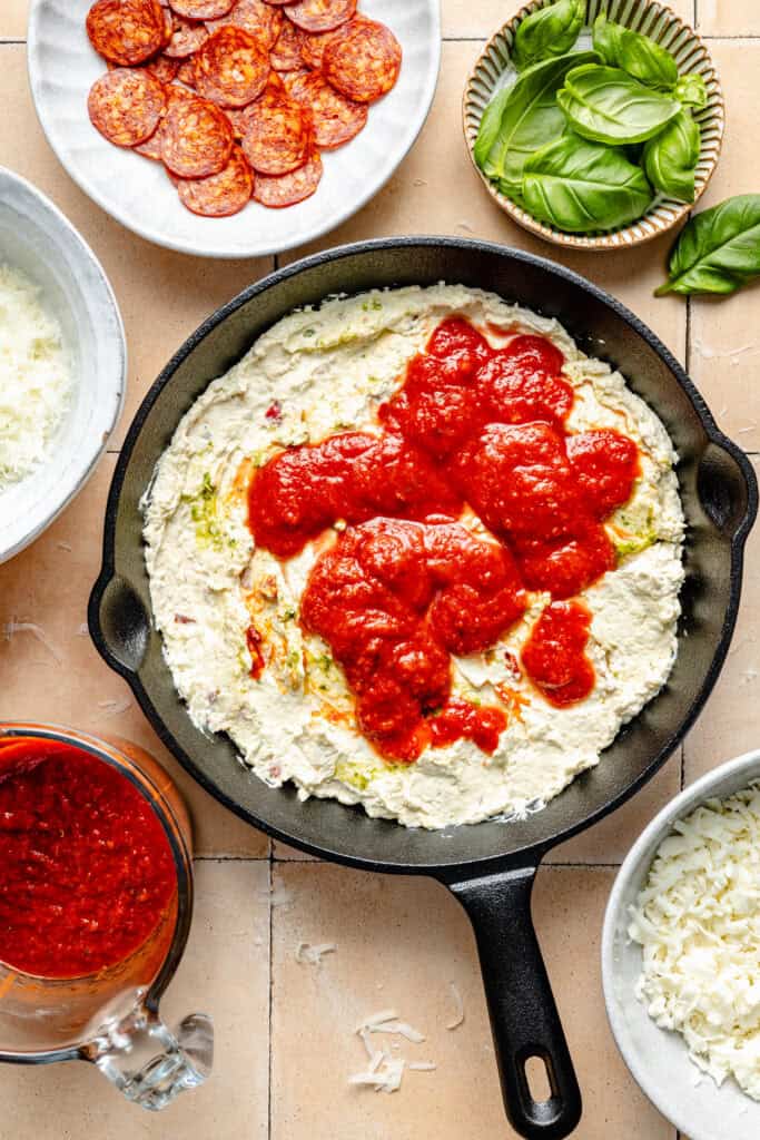 marinara being spread over cream cheese layer