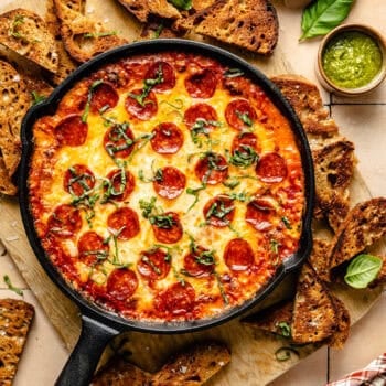 pizza dip topped with basil and surrounded by crusty bread