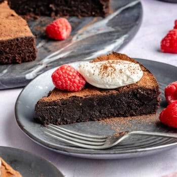 slice of chocolate cake on plate topped with whipped cream and berries