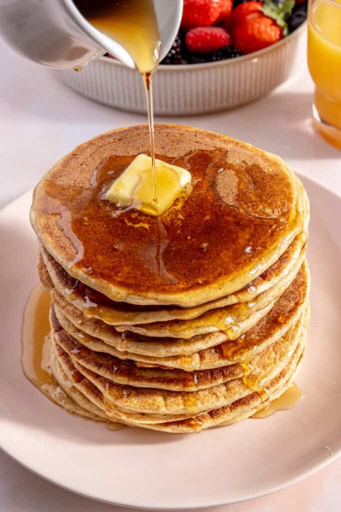 syrup being poured over pancakes