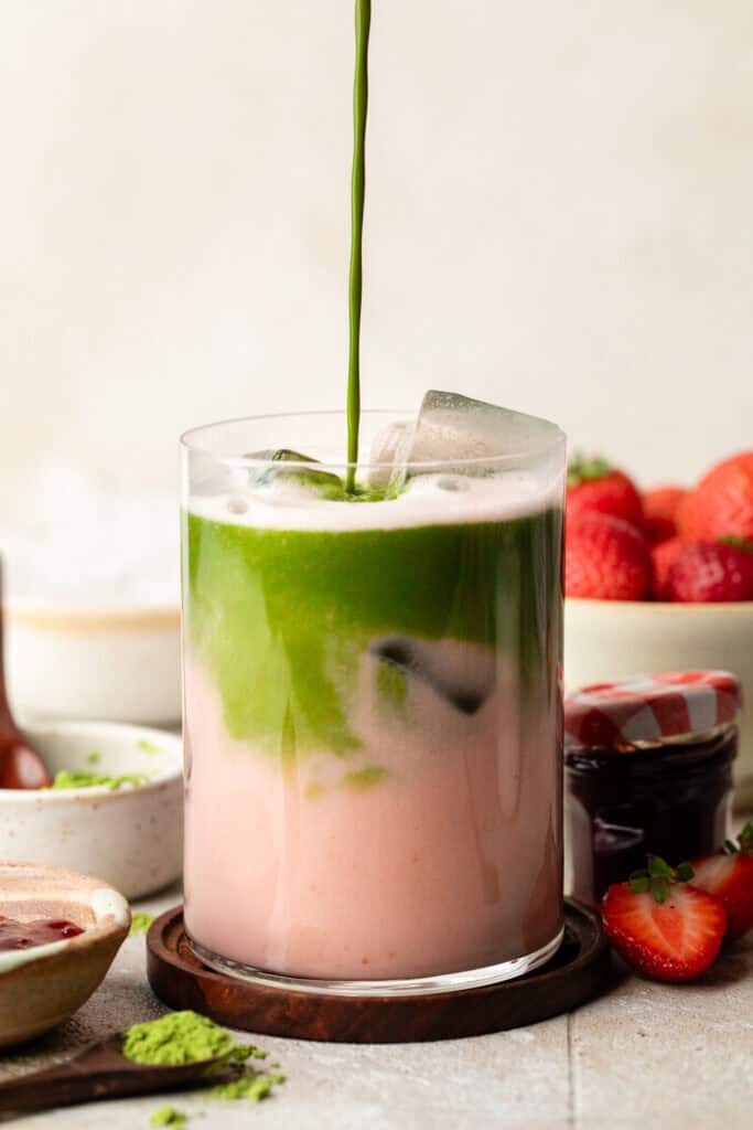 pouring matcha in glass over milk 