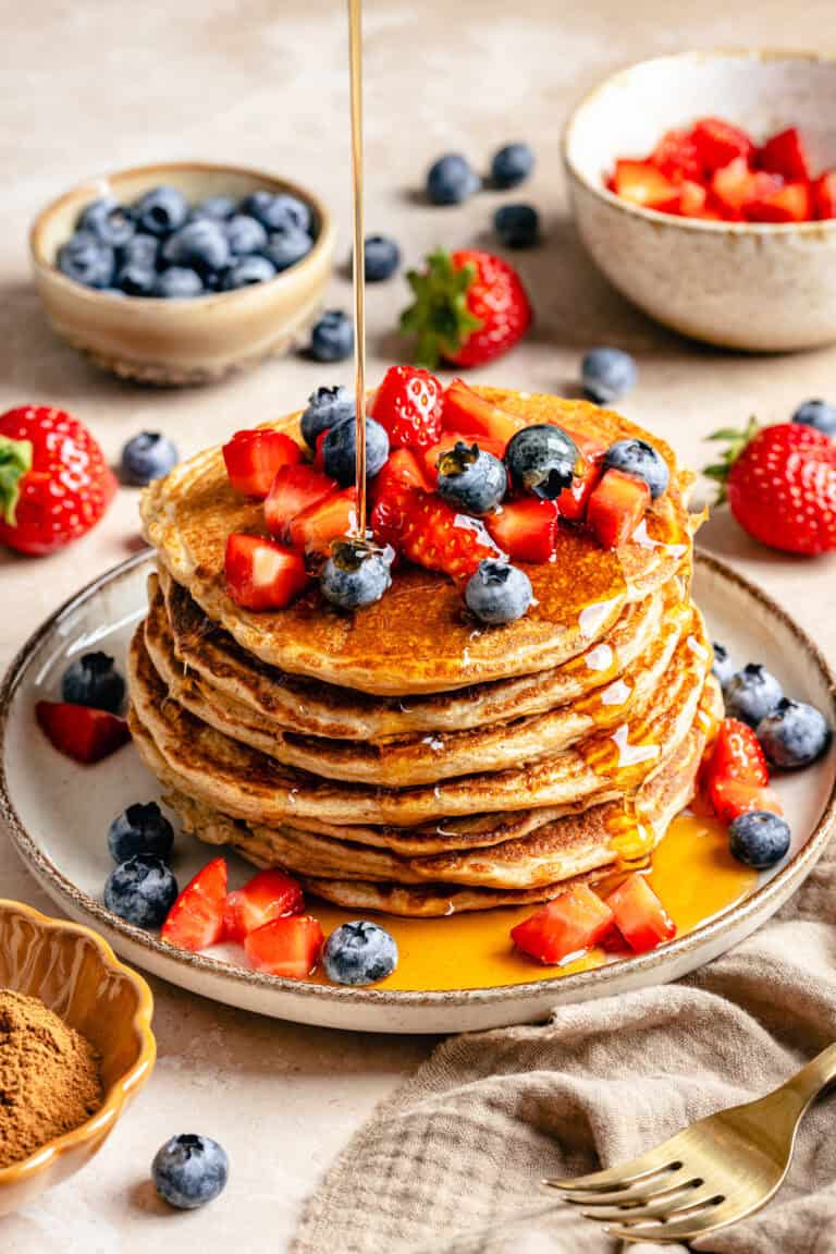stack of cottage cheese pancakes on plate topped with fruit and syrup