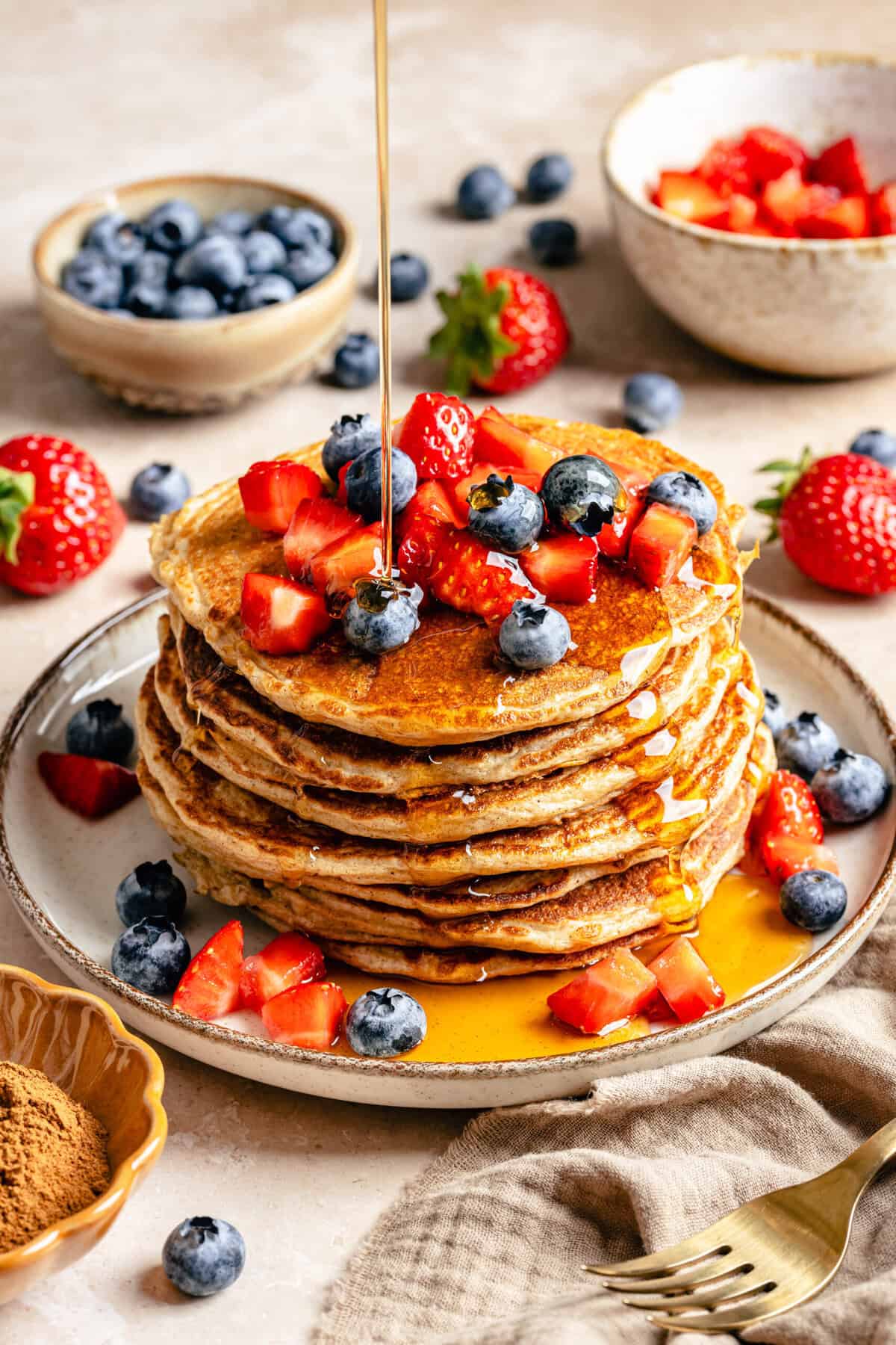 stack of cottage cheese pancakes on plate topped with fruit and syrup