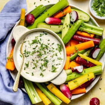 ranch dressing in bowl with spoon and veggies on platter