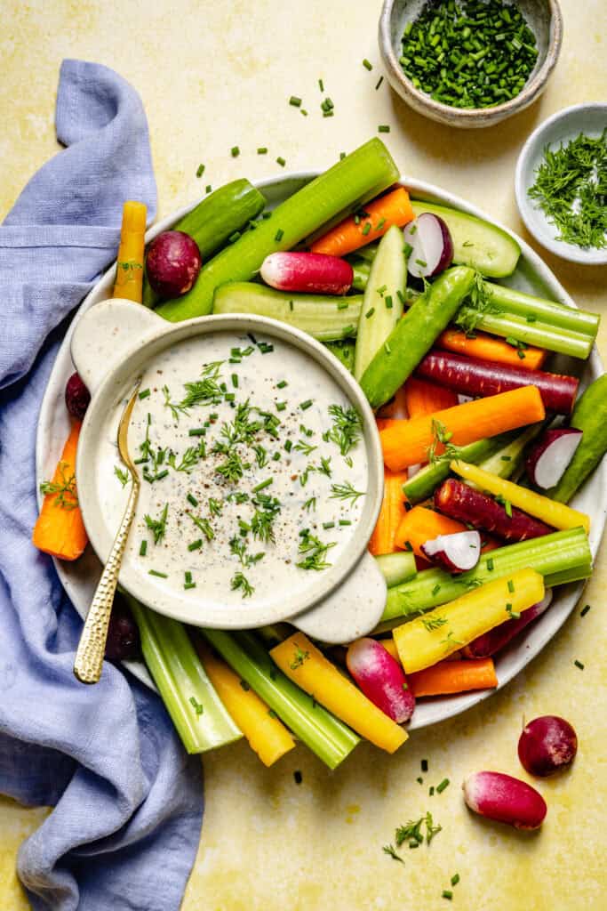 ranch dressing in bowl with spoon and veggies on platter