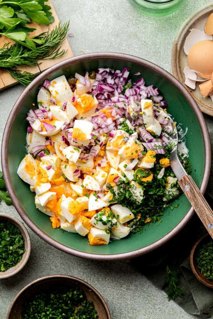 eggs salad ingredients in mixing bowl with spoon