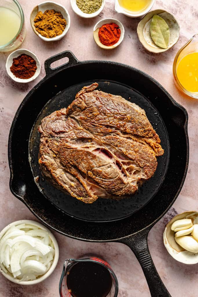 chuck roast being seared in cast iron skillet