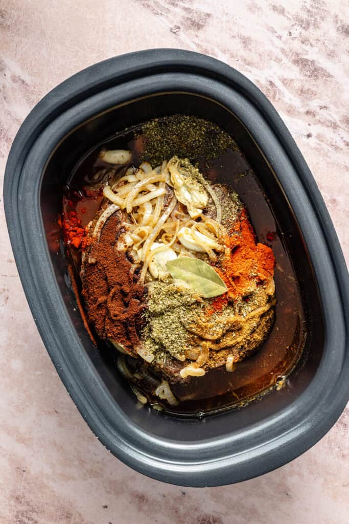 shredded beef and seasonings in slow cooker