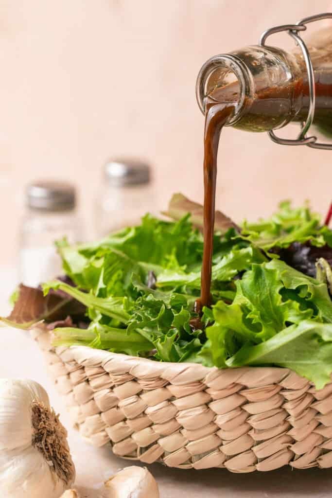 balsamic dressing being poured over greens