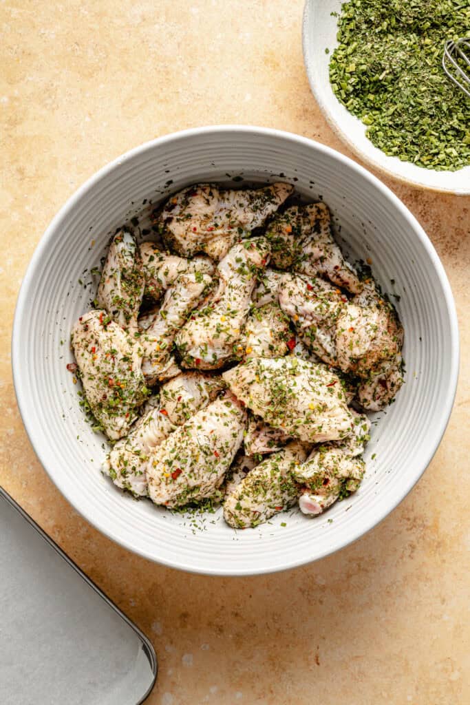 chicken wings in bowl with seasoning