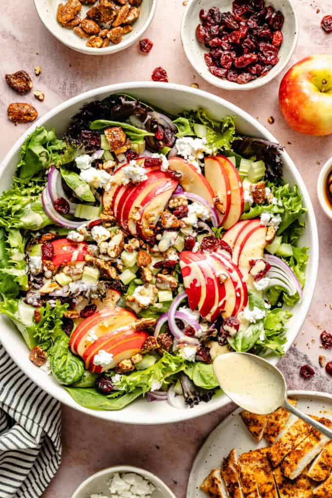 dressing being poured over salad with spoon