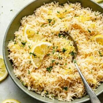 lemon rice in bowl with spoon topped with lemons