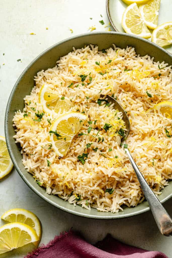 lemon rice in bowl with spoon topped with lemons