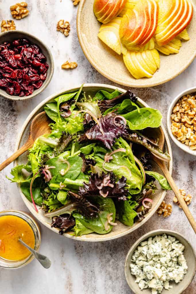 mixed greens in bowl with wooden spoons