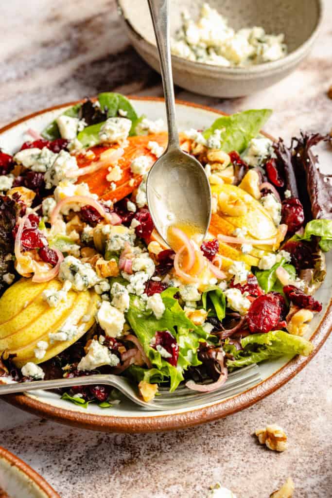 shallot dressing being drizzled over salad