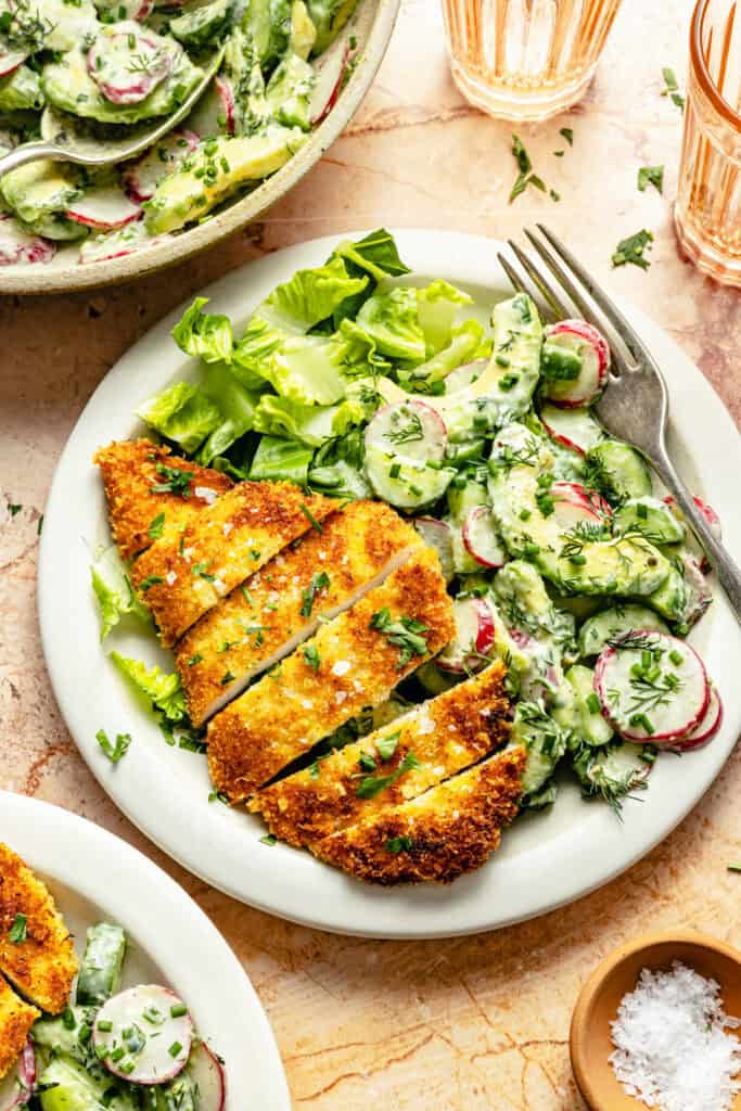 crispy chicken cutlet on plate with cucumber salad