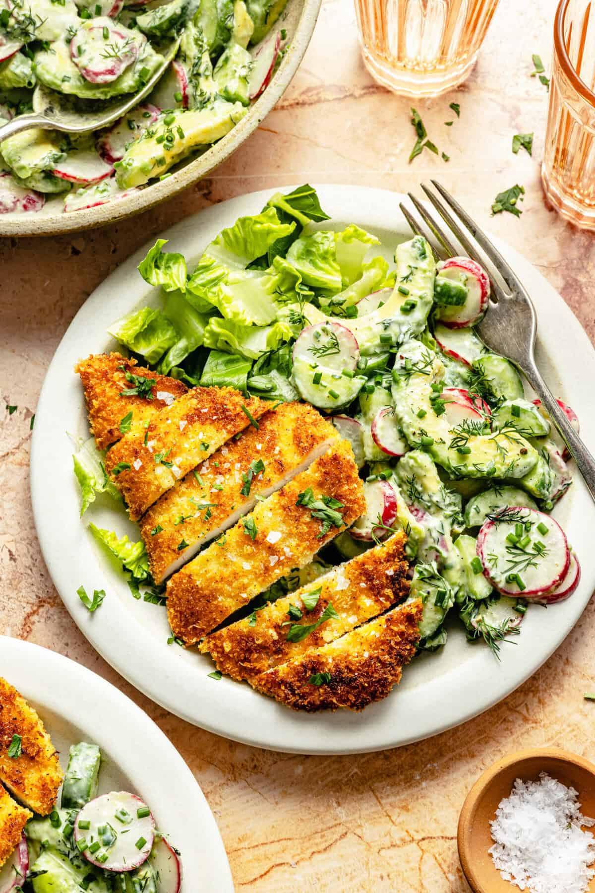 crispy chicken cutlet on plate with cucumber salad