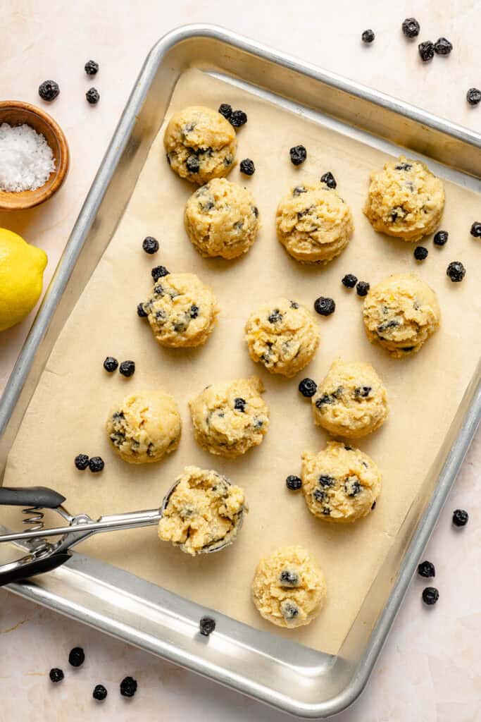 scooping lemon blueberry protein balls on sheet pan