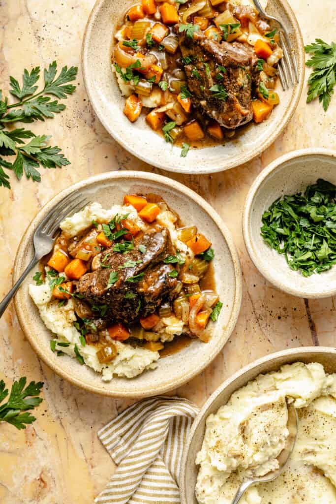 slow cooker short ribs and veggies over mashed potatoes in bowl with fork