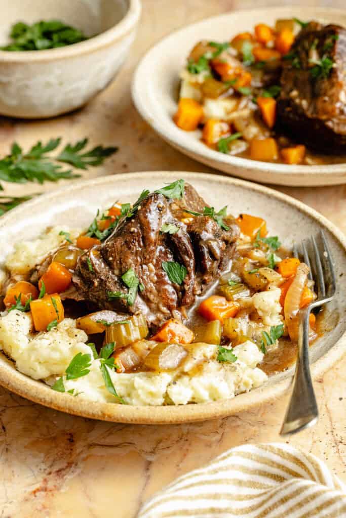 slow cooker short ribs and veggies over mashed potatoes in bowl with fork