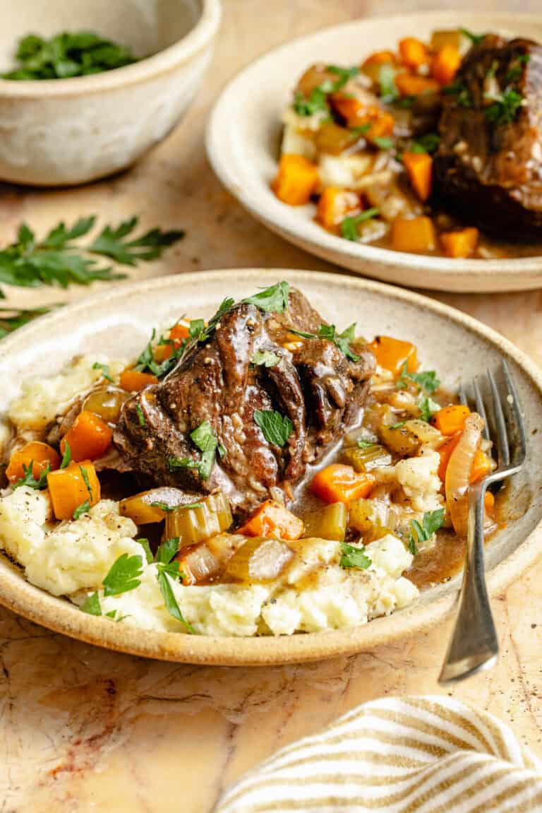 slow cooker short ribs and veggies over mashed potatoes in bowl with fork