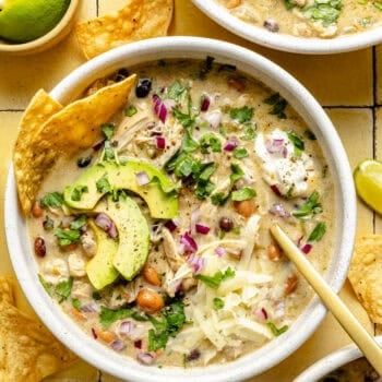 green chicken enchilada soup in a bowl with a spoon and topped with chips